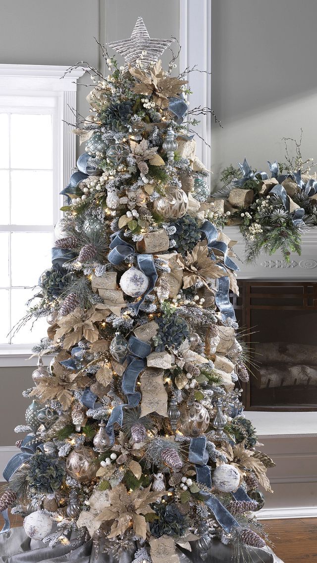 a christmas tree decorated with blue and silver ribbons, ornaments and snowflakes in a living room