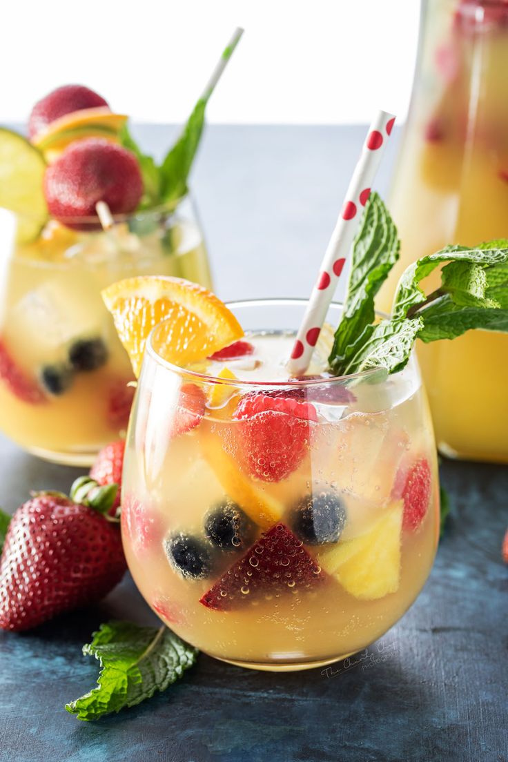 two glasses filled with fruit and ice on top of a table