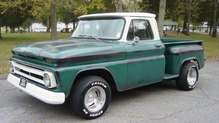 an old green truck parked in a parking lot