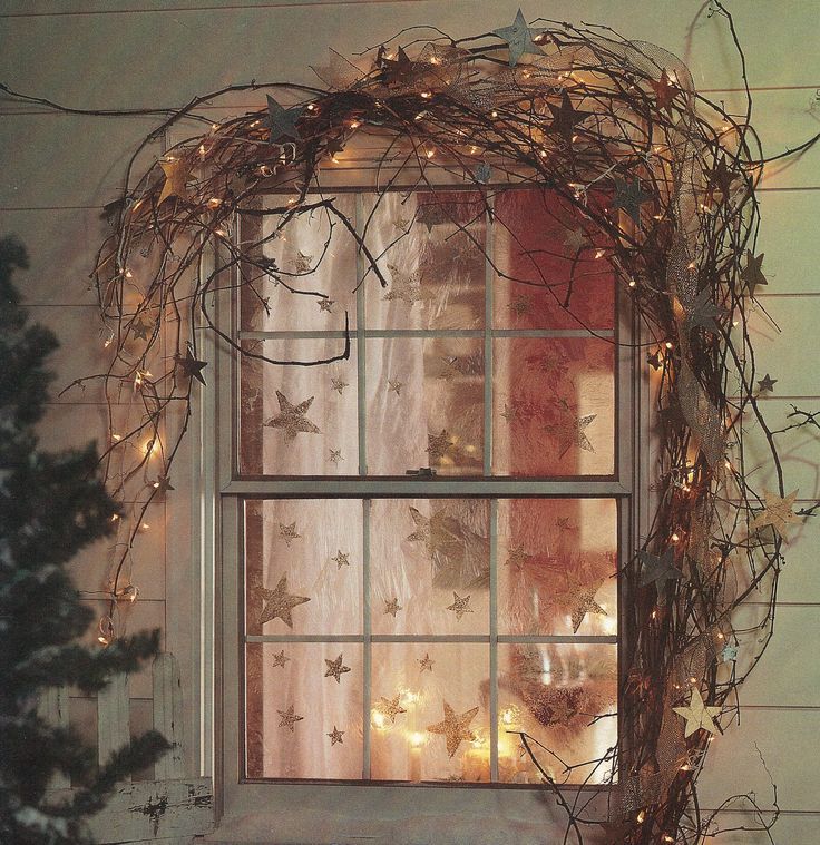 the window is decorated with christmas lights and branches