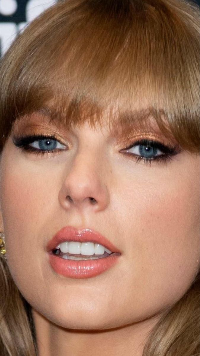 a close up of a person with blonde hair and blue eyes wearing gold earrings