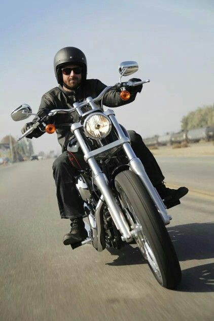 a man riding on the back of a motorcycle down a street