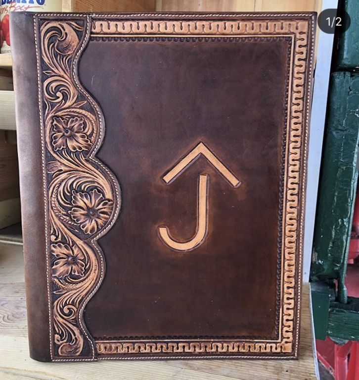 a brown leather book with an arrow on the cover and decorative border around the corner