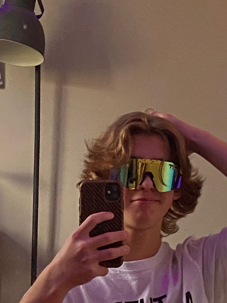 a man taking a selfie in front of a mirror with his cell phone and sunglasses on