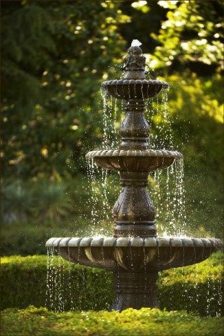 a fountain with water spouting from it's sides in the middle of a garden