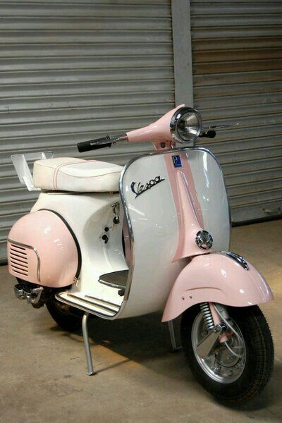 a pink and white scooter parked in front of a garage