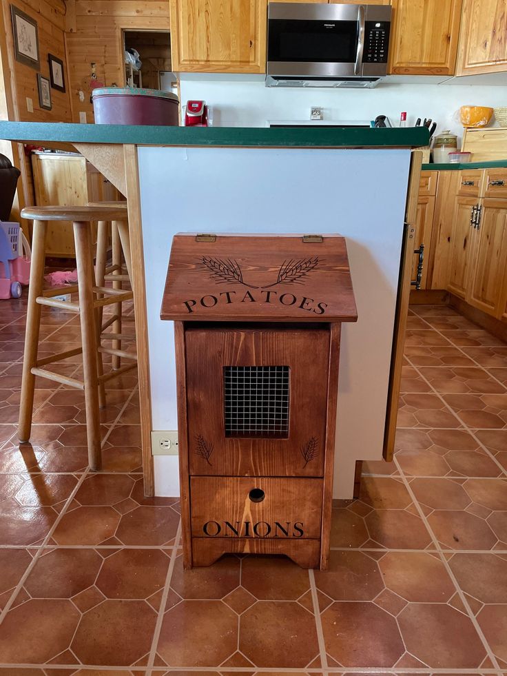 a wooden cabinet sitting in the middle of a kitchen next to a counter and stools