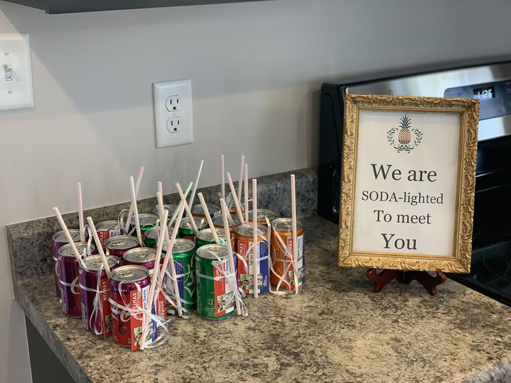 there are many cans on the counter with straws in front of them and a sign that says we are sopa - lighted to meet you