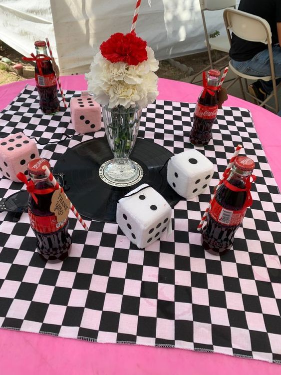 a black and white checkered table cloth with dice, roses and candles on it