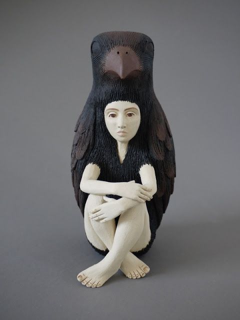 a ceramic sculpture of a woman sitting on the ground