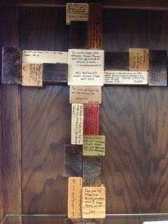 a cross made out of pieces of wood with words written on the bottom and sides