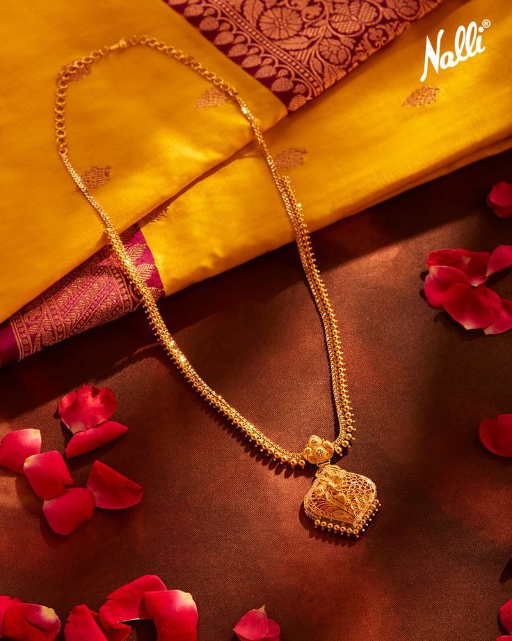 This exquisitely designed gold pendant is crafted in 22-karat gold with an intricately carved floral design pendant and a gold bead pattern on the chain. Pair this beautiful necklace with a Kanchipuram saree, a gold belt, and high heels to complete the look. Gold Neck Chain With Pendant, Long Chain With Pendant Gold Indian, Simple Gold Long Necklace Designs, Tamil Mangalsutra Designs, Gold Pendant Designs Indian, Gold Jewels Design Long Necklace, Gold Chain With Pendant Indian, Gold Long Necklace Indian Bridal, Gold Necklace Designs Long