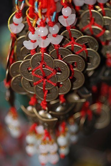 a bunch of coins are hanging from a chandelier with red string and beads