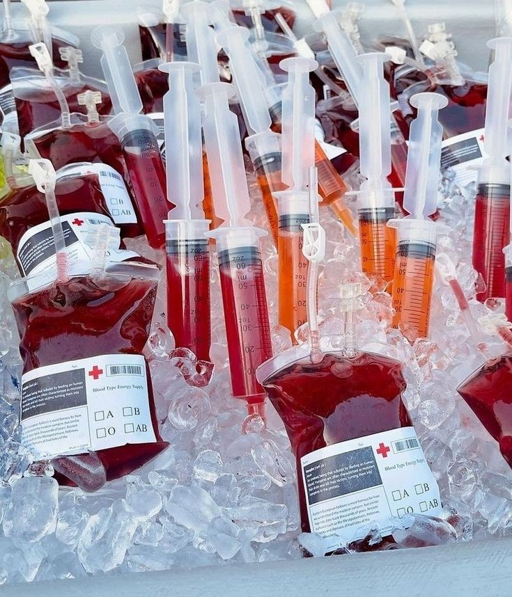 bottles filled with red liquid sitting on top of ice