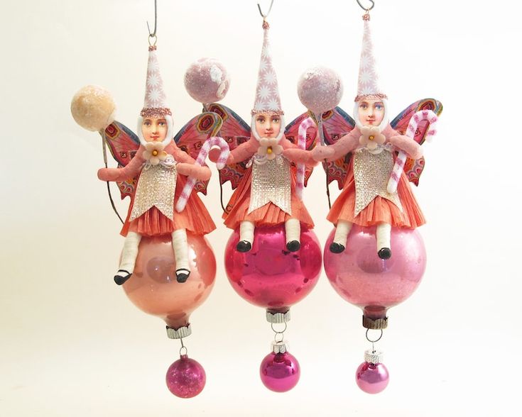 three christmas ornaments are hanging from strings and have angels on them, one is holding an ornament in the shape of a ball