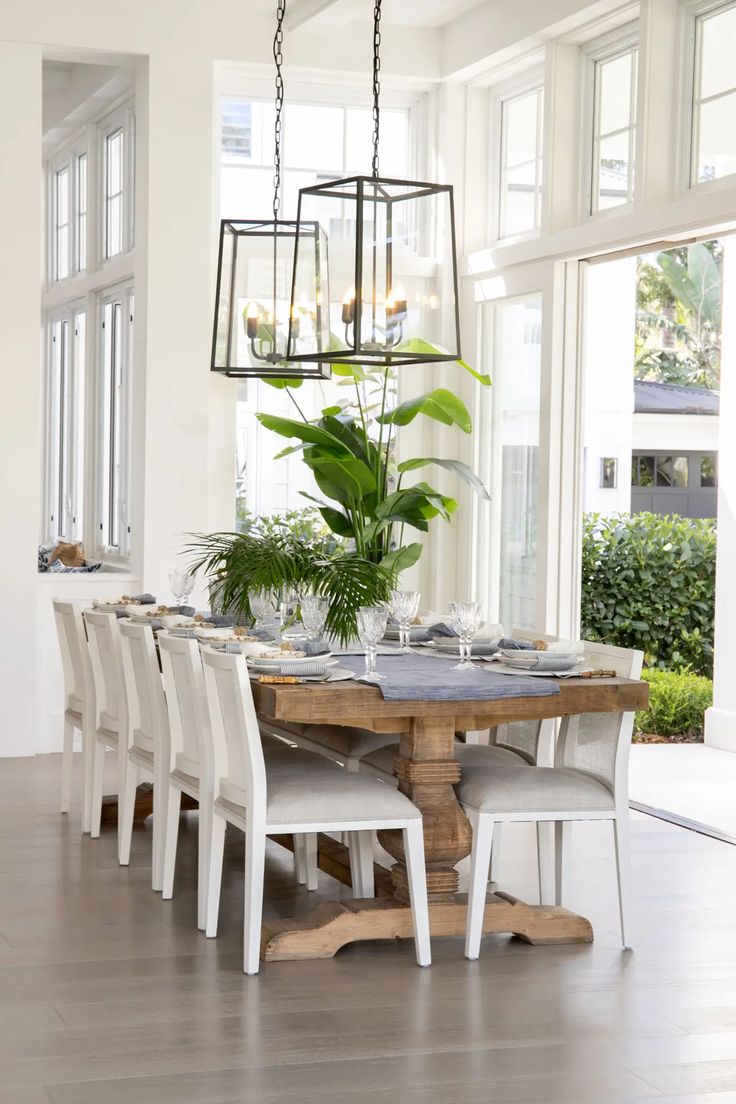 a dining room table with white chairs and a potted plant on top of it