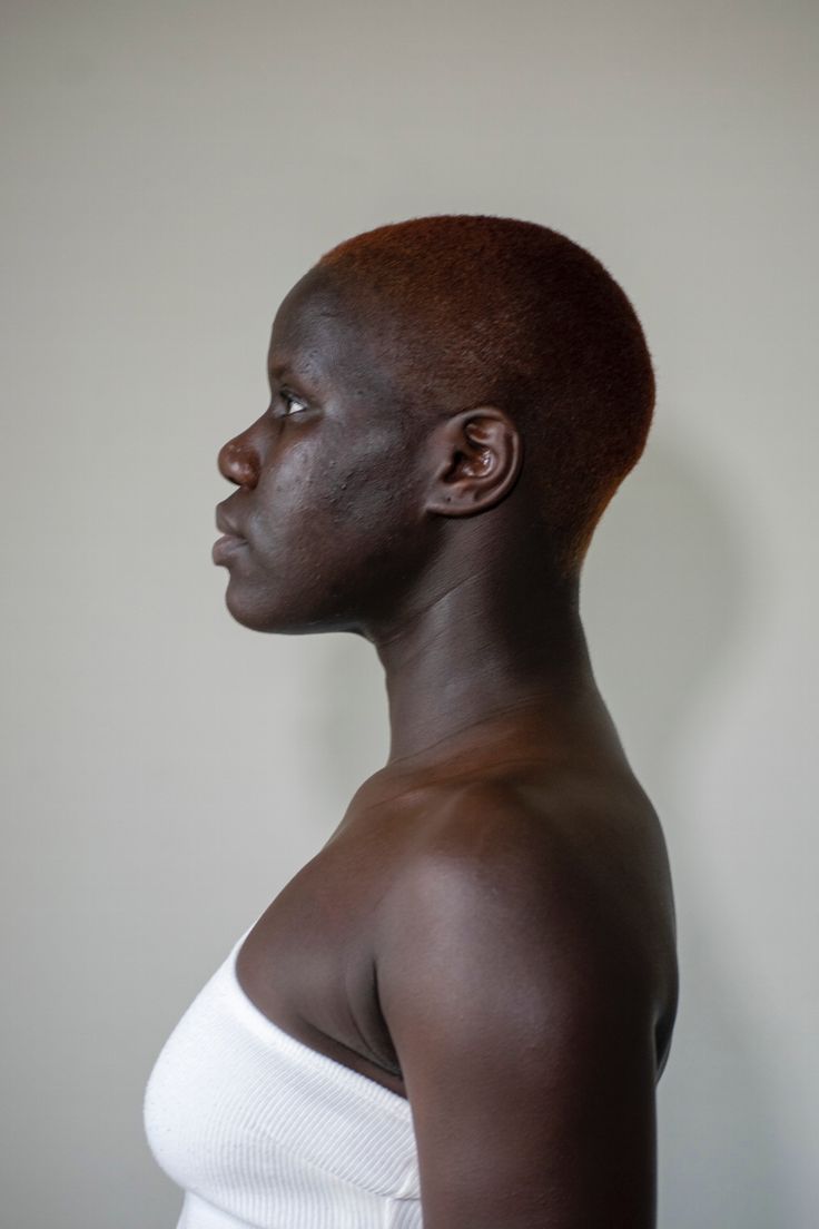 a woman with short brown hair wearing a white top and looking off to the side