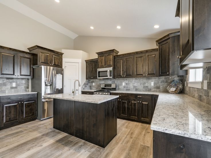 a large kitchen with wooden cabinets and marble counter tops