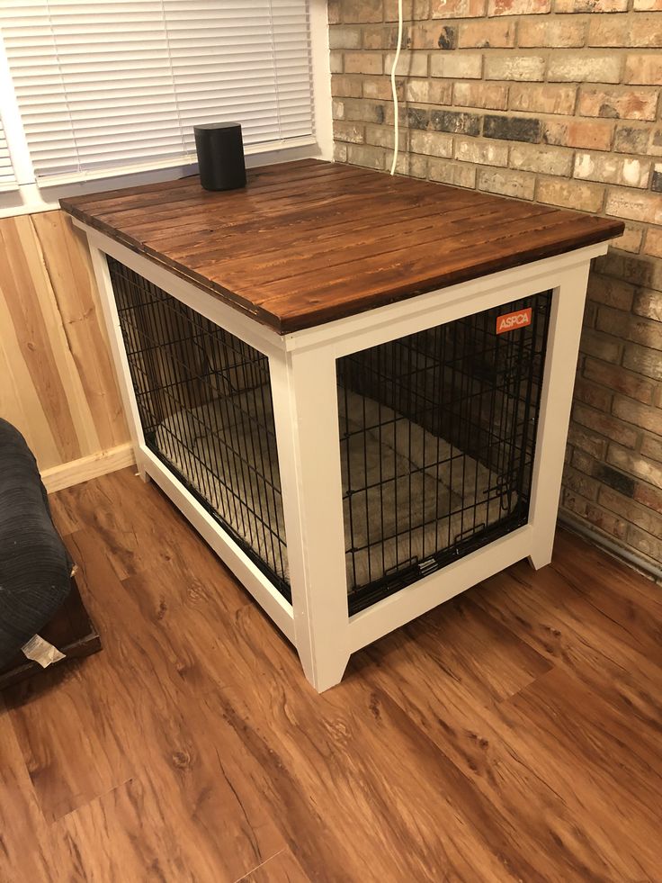 a dog crate sitting on top of a hard wood floor next to a brick wall