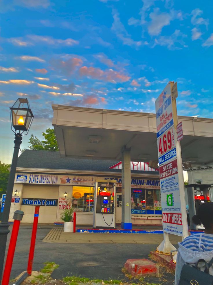 a gas station with several signs in front of it and a blue sky behind them