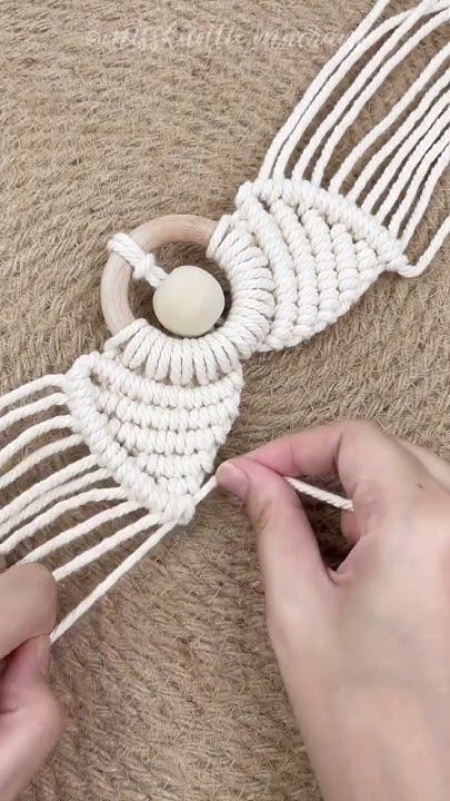 someone is working on something that looks like a dream catcher with white yarn and beads