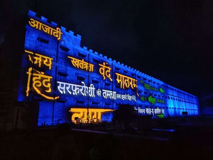 an illuminated building in the dark with blue and yellow lights on it's side