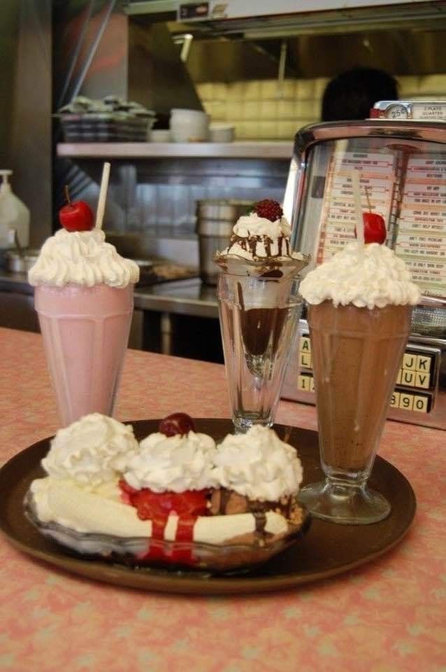 three desserts on a plate with ice cream and strawberries in the middle, along with milkshakes