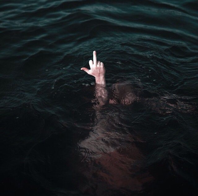 a person floating in the water with their hand up