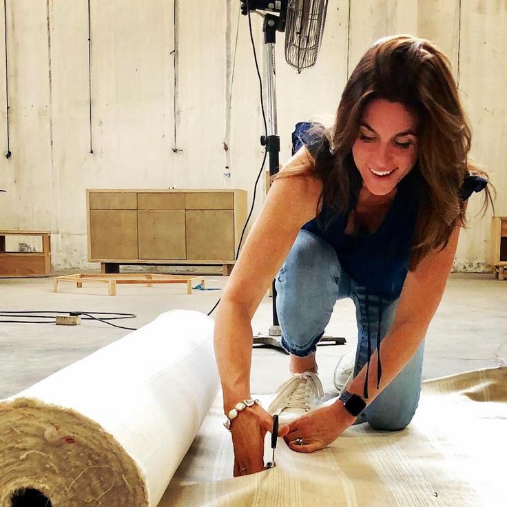 a woman is laying on the floor next to a roll of fabric and smiling at the camera