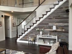 a living room filled with furniture and a stair case in front of a wooden wall