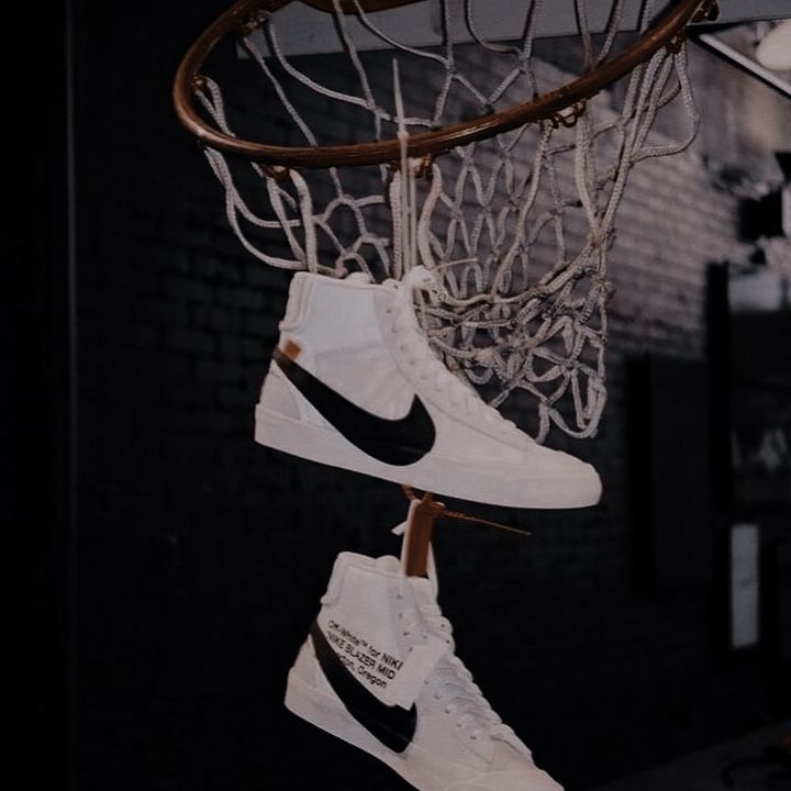 two pairs of shoes are hanging from a basketball hoop with the word nike written on it