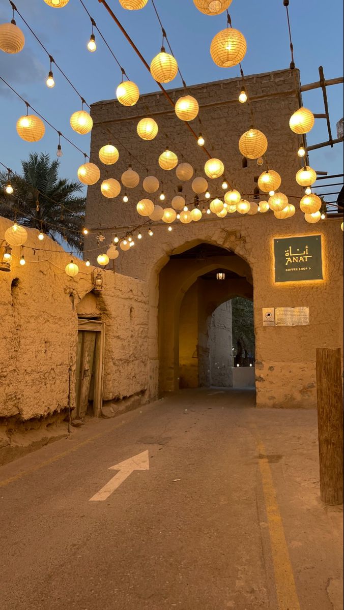 an archway with lanterns hanging from it's sides and lights on the ceiling above