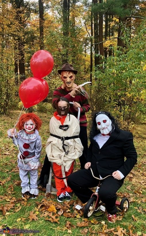 three people in costumes posing for a photo with two clowns and one baby on a tricycle