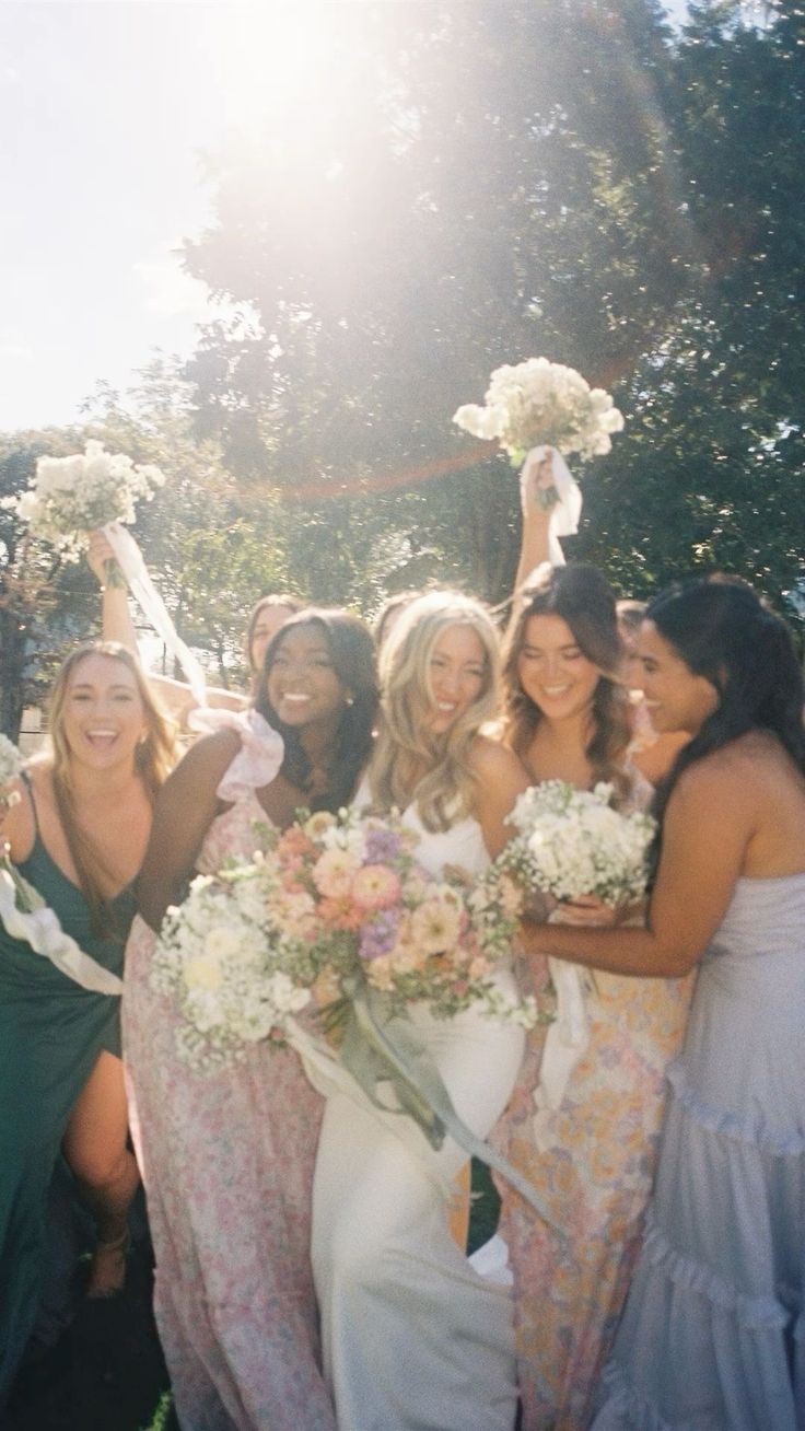 a group of women standing next to each other holding bouquets in their hands and posing for the camera