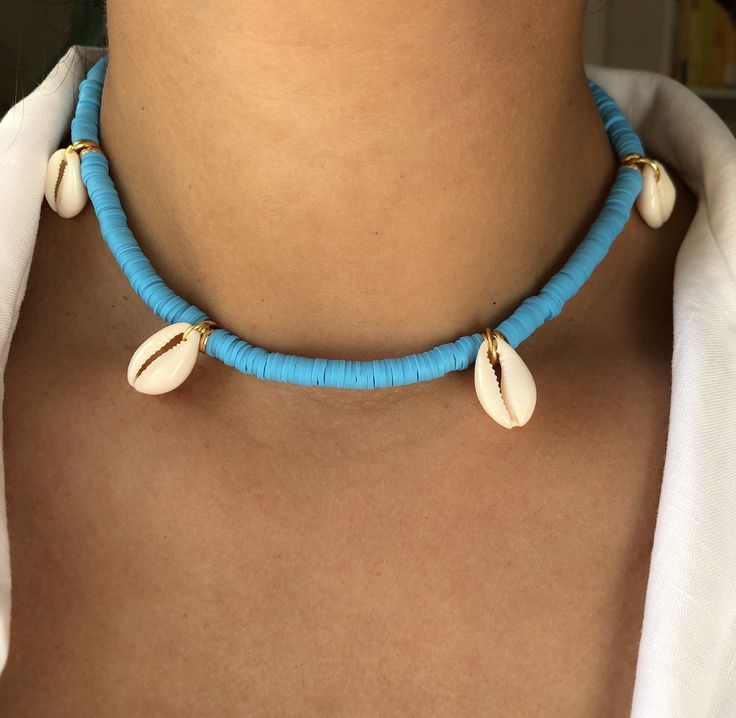 DEEP DIVE (Blue) * Ultimate Modern Boho Summer Necklace * Blue Enamel Coin Beads (6mm) * Natural cowrie shells * Stainless steel chain and carabiner in gold (no fading) * Full chain length: 45cm * Adjustable: yes * Beachworthy * Good vibes only! ➪  𝐴𝑙𝑙 𝑃𝑟𝑜𝑑𝑢𝑐𝑡𝑠 𝑎𝑟𝑒 𝑐𝑎𝑟𝑒𝑓𝑢𝑙𝑙𝑦 𝑝𝑎𝑐𝑘𝑎𝑔𝑒𝑑 𝑤𝑖𝑡ℎ 𝑙𝑜𝑣𝑒.  ➪  𝑃𝑎𝑐𝑘𝑎𝑔𝑒 𝑖𝑛𝑐𝑙𝑢𝑑𝑒𝑠: 𝐼𝑡𝑒𝑚 (𝑜𝑓 𝑐𝑜𝑢𝑟𝑠𝑒), 𝑎 𝑙𝑜𝑣𝑒𝑙𝑦 𝑉𝑒𝑙𝑣𝑒𝑡 𝐺𝑖𝑓𝑡 𝑏𝑎𝑔. ✲ 𝑇ℎ𝑒 𝑟𝑒𝑐𝑜𝑚𝑚𝑒𝑛𝑑𝑒𝑑 𝑐ℎ𝑎𝑖𝑛 𝑠𝑖𝑧𝑒 𝑓? Handmade Blue Necklaces For The Beach, Handmade Blue Necklaces For Beach, Handmade Blue Strand Jewelry, Light Blue Round Beads Necklace For The Beach, Blue Strand Necklace For Beach, Adjustable Blue Beachy Necklace, Blue Beachy Necklace, Light Blue Round Bead Necklaces For The Beach, Blue Strand Necklace With Beachy Style