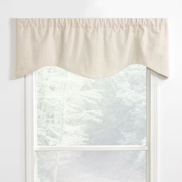 a white window with a beige valance hanging from it's side in front of a forest