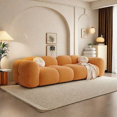 an orange couch sitting on top of a rug in a living room