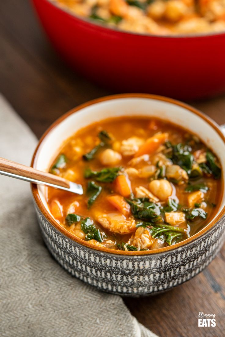 a bowl of soup with spinach and chickpeas in it on a wooden table