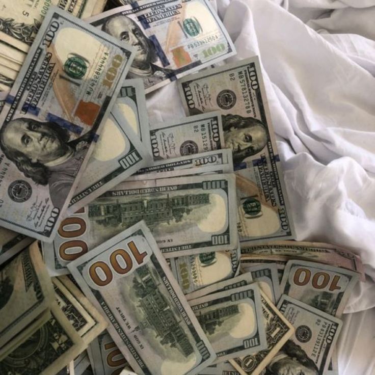 a pile of twenty dollar bills laying on top of a white cloth covered bed sheet