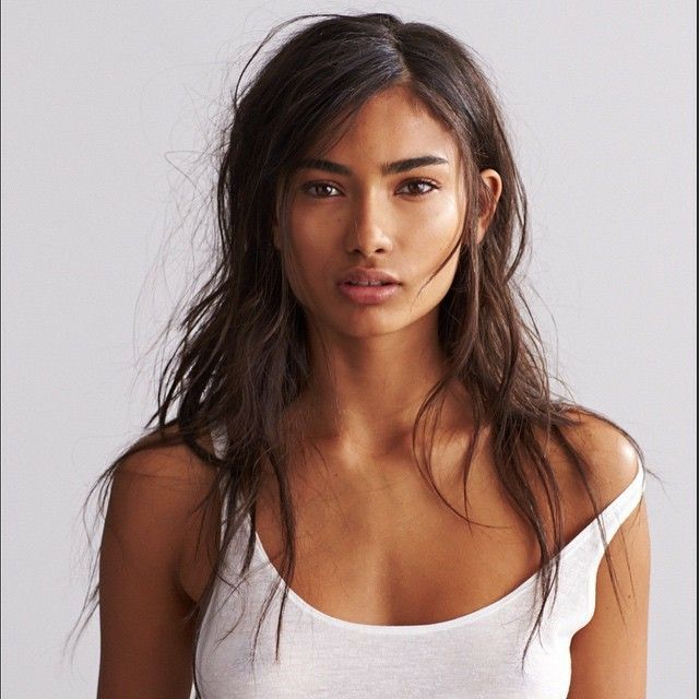 a woman with long hair wearing a white tank top