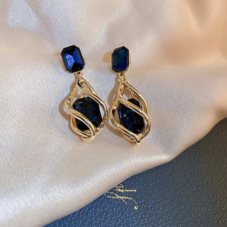 Luxury sapphire earrings Set with sapphires as quiet and deep as the sea, these artificial sapphire earrings impress with their luxury and elegance. The large and small artificial sapphires are both square and have many flat cuts that make the blue sapphire earrings look like fine works of art. The large sapphire of sapphire drop earrings sits in a cage of golden arcs no less than the queen's crown. These sapphire drop earrings are the perfect pair for formal outfits to make you stand out from t Sapphire Drop Earrings For Party, Elegant Blue Crystal Earrings, Elegant Sapphire Crystal Earrings, Sapphire Drop Crystal Earrings, Elegant Sapphire Crystal Earrings For Pierced Ears, Elegant Sapphire Crystal Drop Earrings, Blue Crystal Earrings, Crystal Dangle Earrings, Flatlay Styling