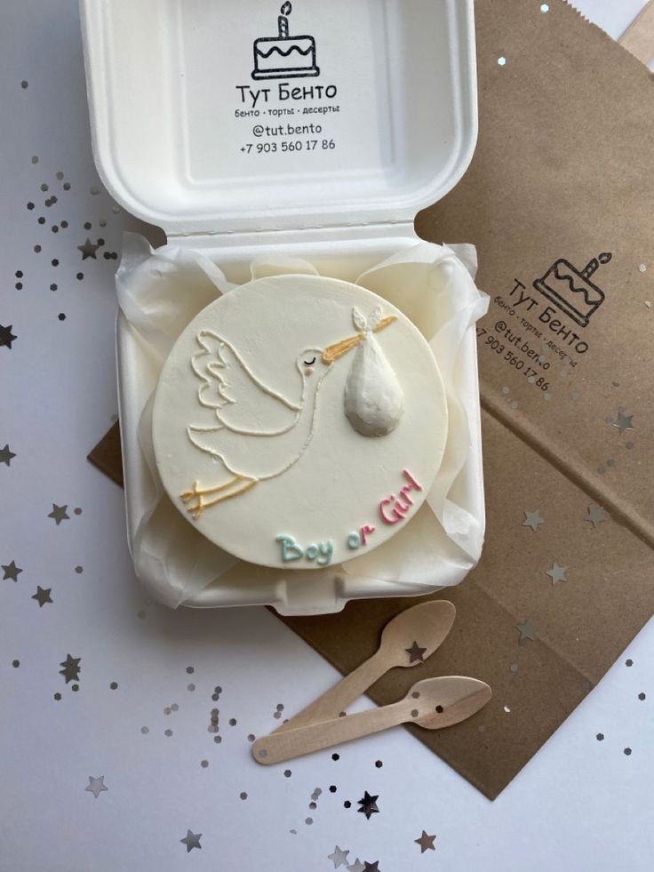 a stork shaped cake in a box with scissors on the table next to it