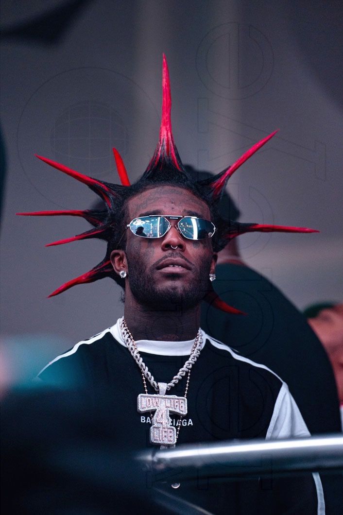 a man with red spikes on his head wearing sunglasses and a black t - shirt