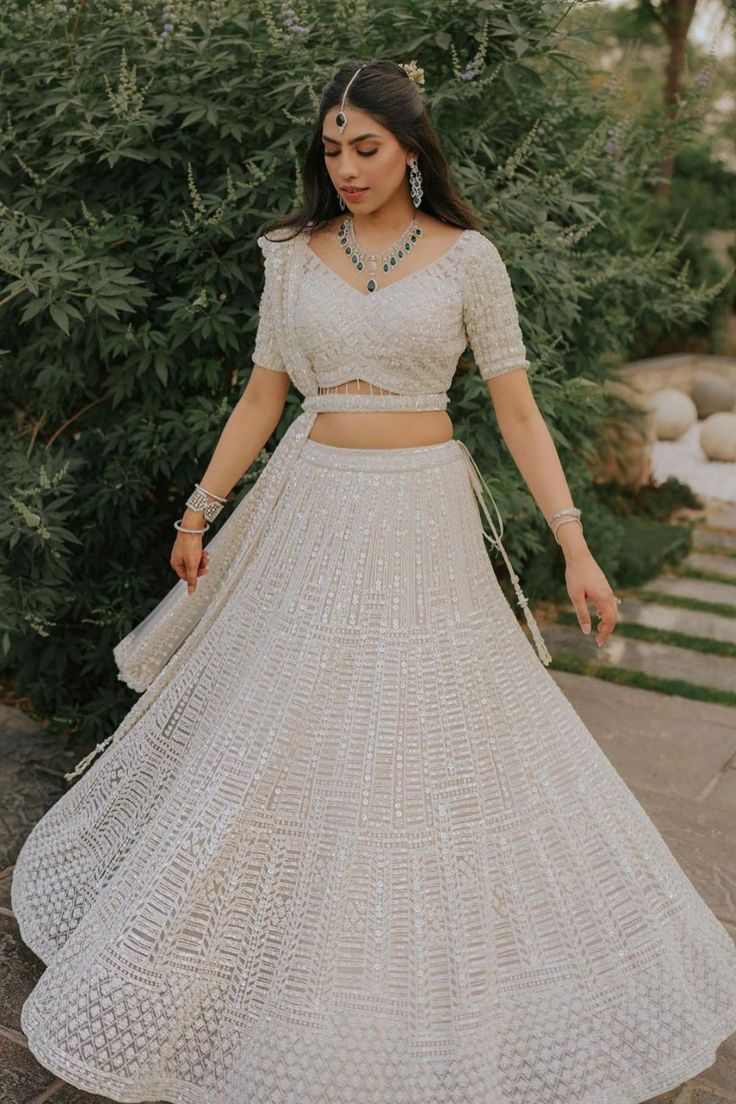 a woman in a white dress is standing outside