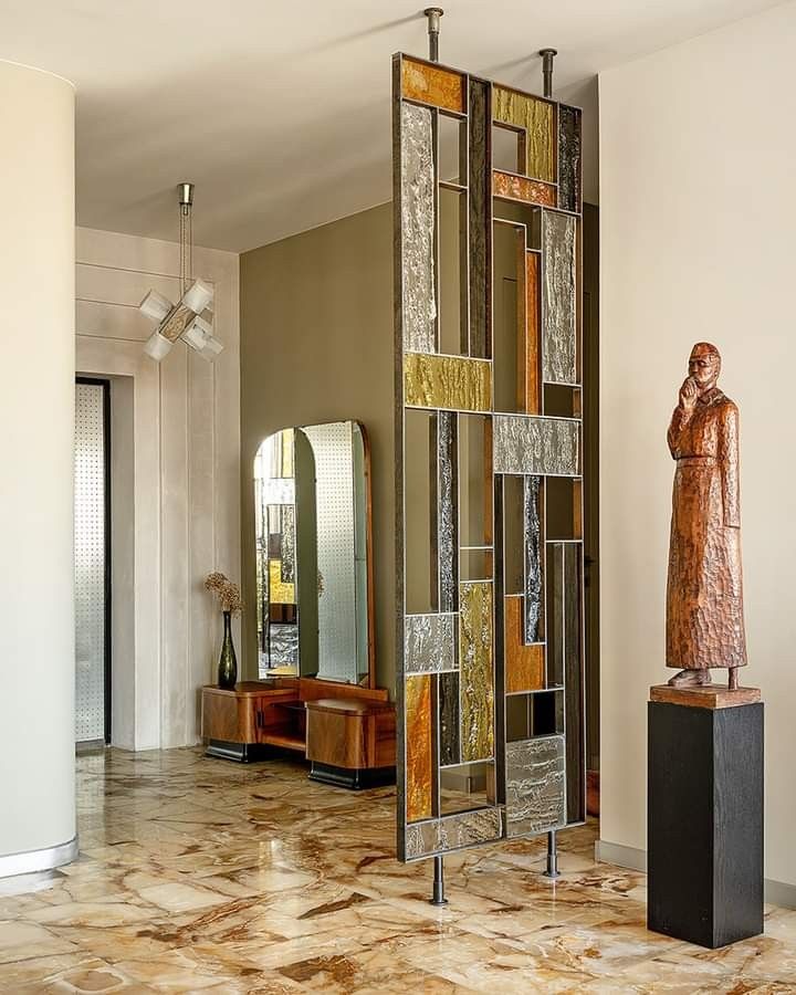 a large mirror sitting on top of a tiled floor next to a statue in a living room