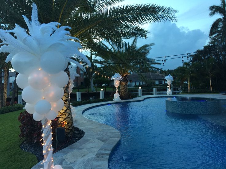 an outdoor pool decorated with white balloons and lights