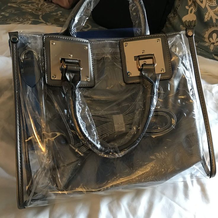 This satchel and tote handbag is 2-in-1. It's a transparent satchel tote with a complimentary removable shoulder bag. This bag is awesome! If you love chic bags, this is the perfect bag for you!

2-day processing. Shipped in 4-7 days. Trendy Silver Satchel For Shopping, Everyday Use Satchel Shoulder Bag With Clear Strap, Travel Crossbody Satchel With Clear Strap, Rectangular Bags With Clear Strap For On-the-go, Clear Strap Shoulder Bag For Shopping, Everyday Clear Satchel With Removable Pouch, Clear Travel Bag With Removable Pouch, Clear Satchel With Removable Pouch, Everyday Satchel With Clear Strap And Crossbody Shape