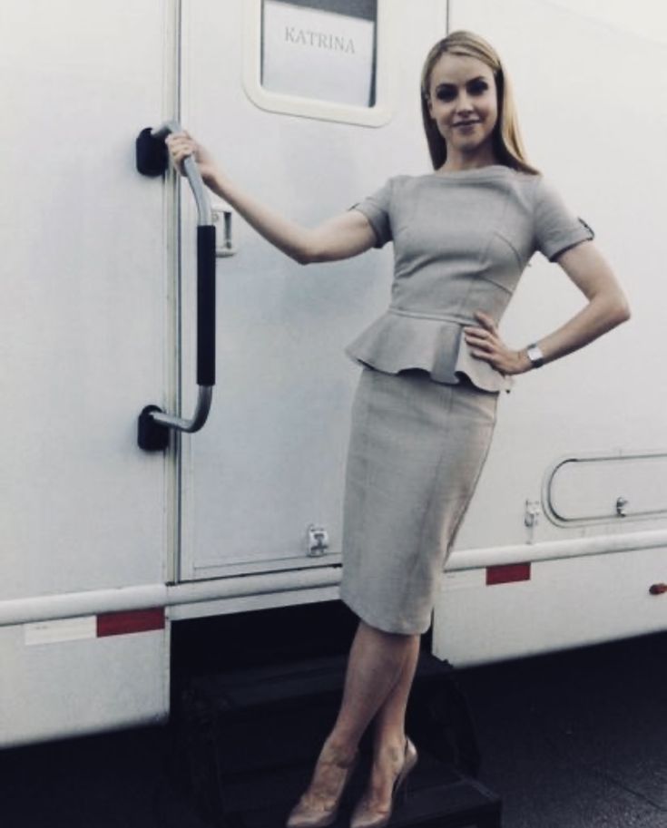 a woman standing in front of a white trailer with her hand on the door handle