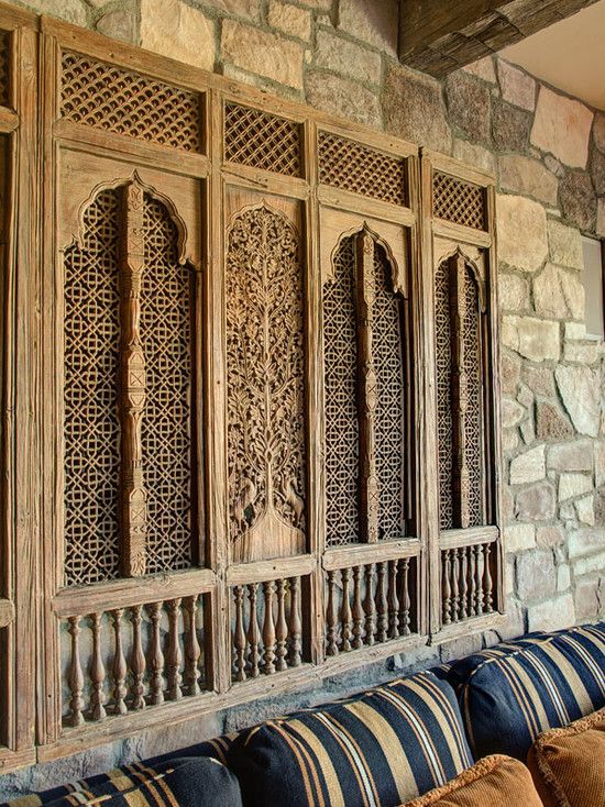 an ornately carved wooden wall with striped pillows on the couches in front of it