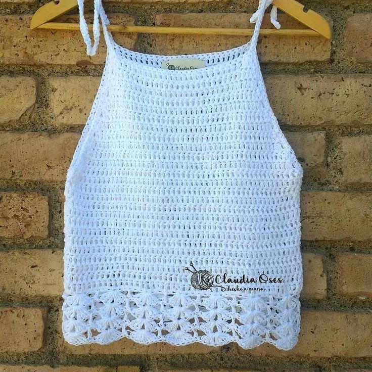 a white crocheted top hanging on a brick wall